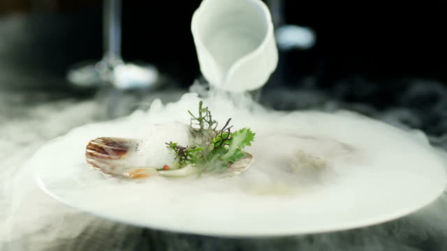 Chef Garnishing Scallops with Dry Ice in Luxury Restaurant. Close-Up.